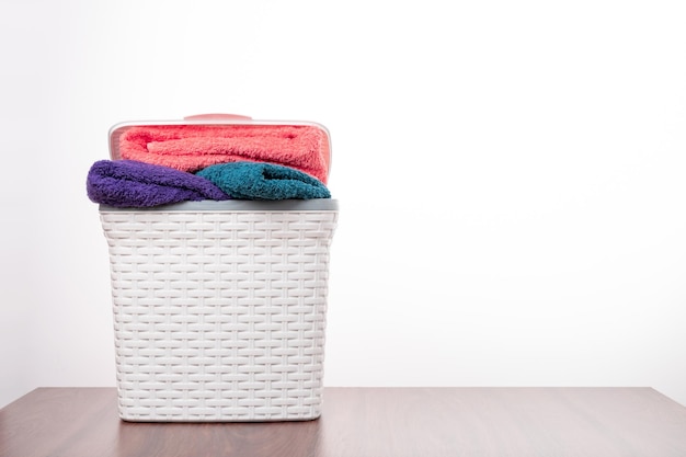 Фото Стопка свежих чистых полотенец в плетеной корзине на столе