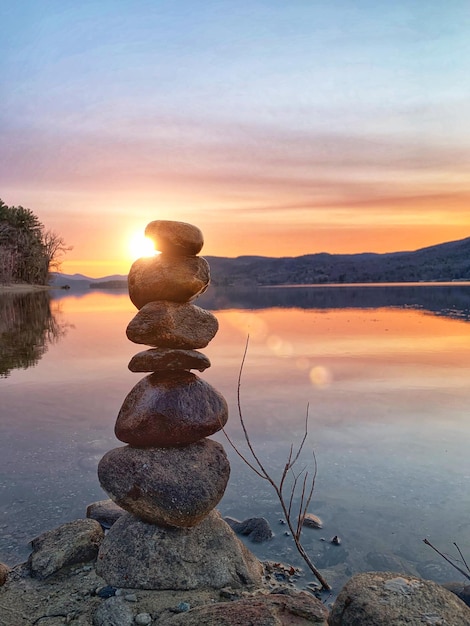 写真 夕暮れの空を背景にビーチに積もった石