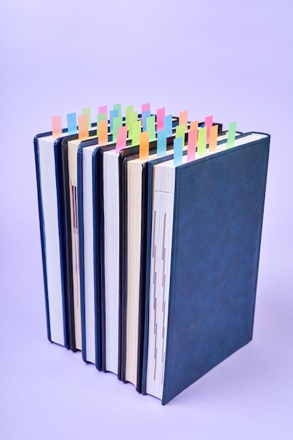 A stack of office notepads with colorful sticky page markers sandwiched between pages