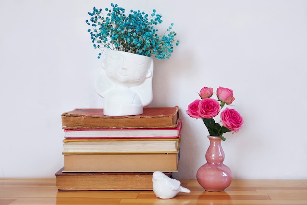 A stack of old books with vases of flowers.