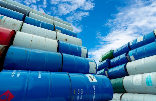 Photo stack of old chemical barrels. blue, green, and red oil drum. steel oil tank. toxic waste warehouse. hazard chemical barrel with red flammable liquid warning label. hazard waste storage in a factory.