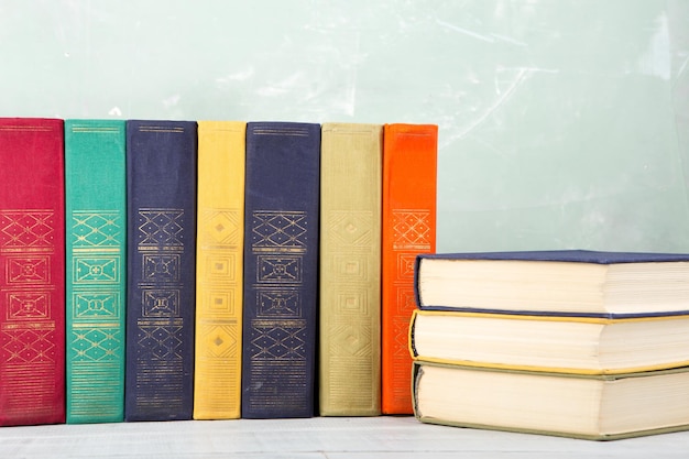 a stack of old colored books on shelf and green background