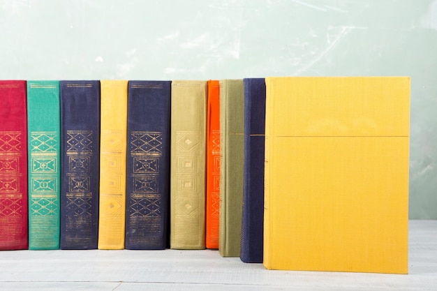 A stack of old colored books on shelf and green background