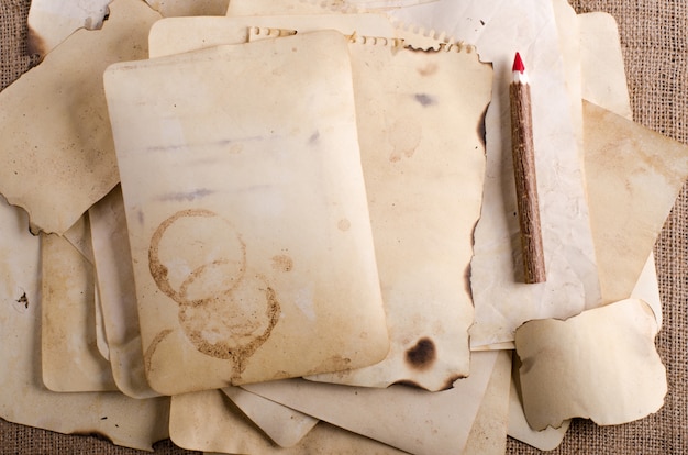 Stack old papers, notebook and wooden pencils on burlap, sackcloth.