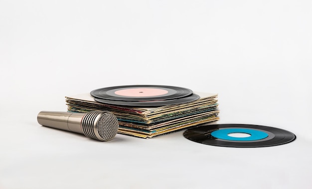 Photo a stack of old vinyl records and a microphone for karaoke on a white background