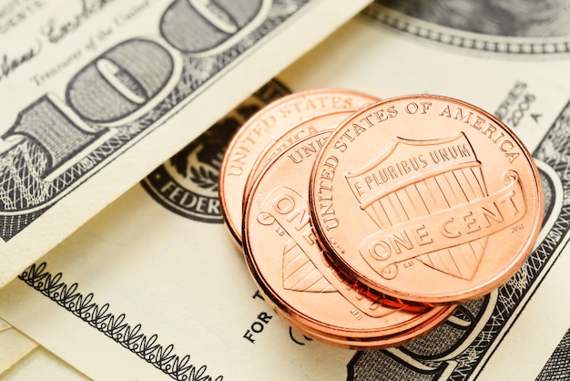 Стек монет США в один цент с несколькими стодолларовыми купюрами
