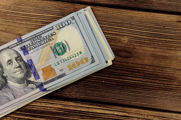 Stack of one hundred dollars bills on wooden desk