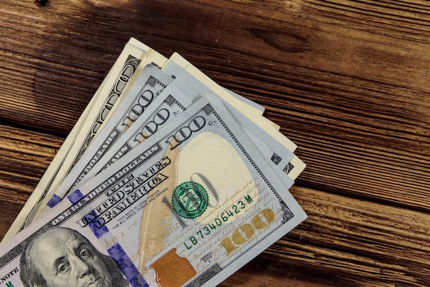 Stack of one hundred dollars bills on wooden desk