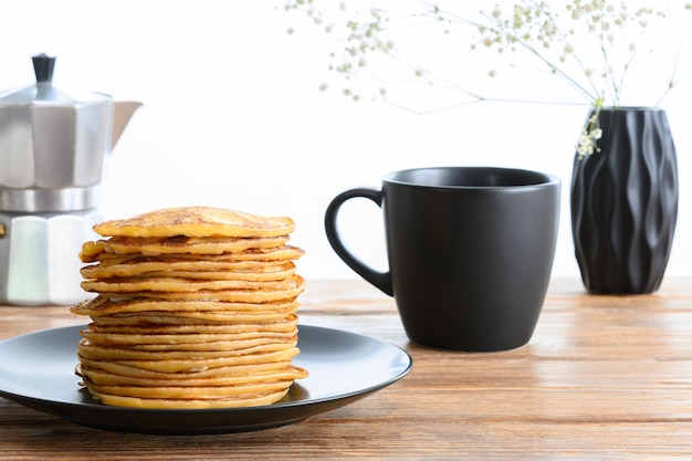 Stack of pancakes dark mug and coffee pot on wooden table side view