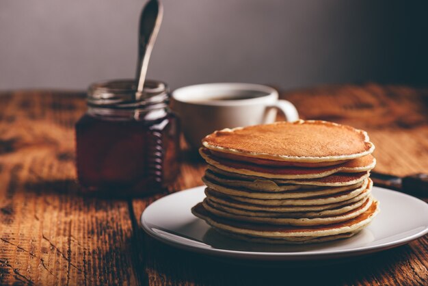 Stack of pancakes on white plate over wooden surface