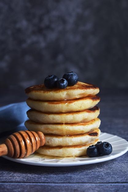 a stack of pancakes with blueberries and a spoon with honey