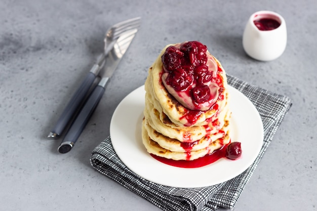 Stack of pancakes with cherry sauce and chocolate on a white plate. Breakfast.