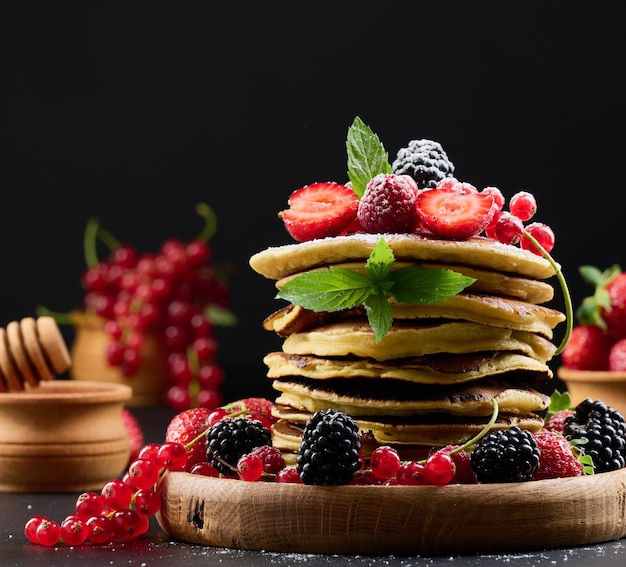 A stack of pancakes with fresh fruit sprinkled with powdered sugar