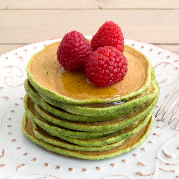 A stack of pancakes with honey and raspberry.