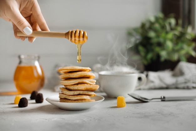 Foto pila di pancake con lo sciroppo di miele su fondo di legno bianco