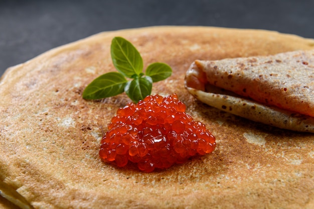 Stack of pancakes with red caviar, close up