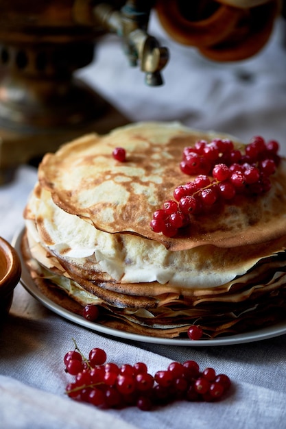 Stack of pancakes with red juicy currants