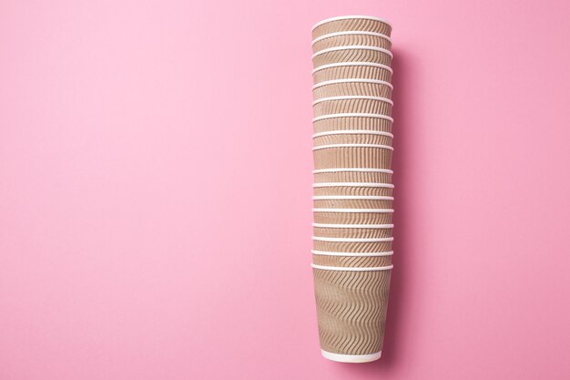 A stack of paper cups for hot drinks on a pink isolated background.