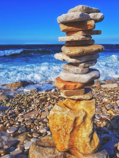 Stack of pebbles on beach against sky