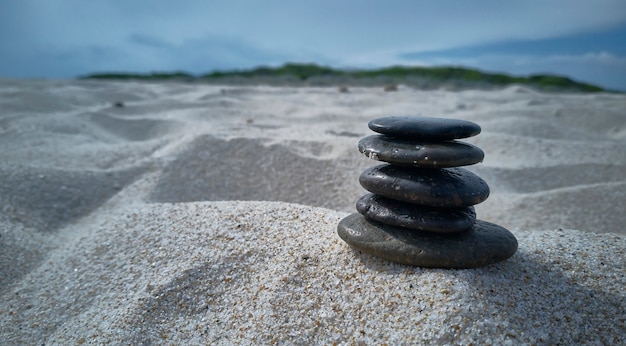 Stack of pebbles on the beach sand: Zen evocative image of inner peace, tranquility and general satisfaction.