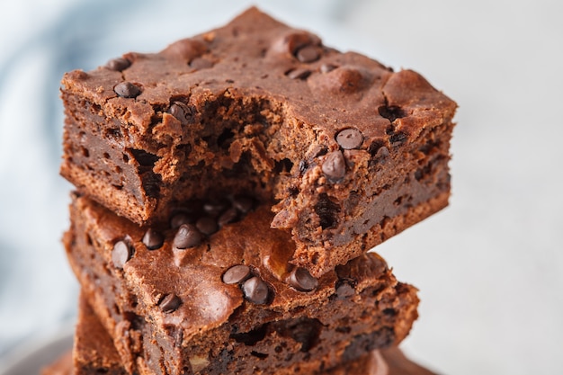 Impila pezzi di torta al cioccolato vegano con gocce di cioccolato e noci.