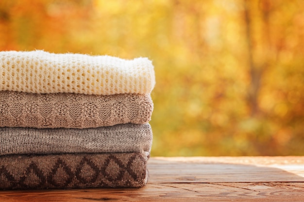 Stack pile of knitted autumn clothes on nature.