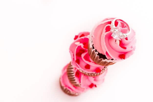 Stack of pink cupcakes with engagement ring on top.