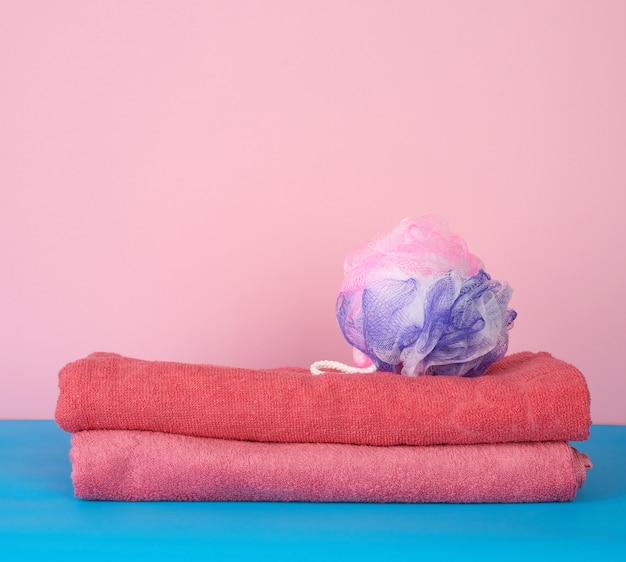 Stack of pink folded towels and a plastic washcloth