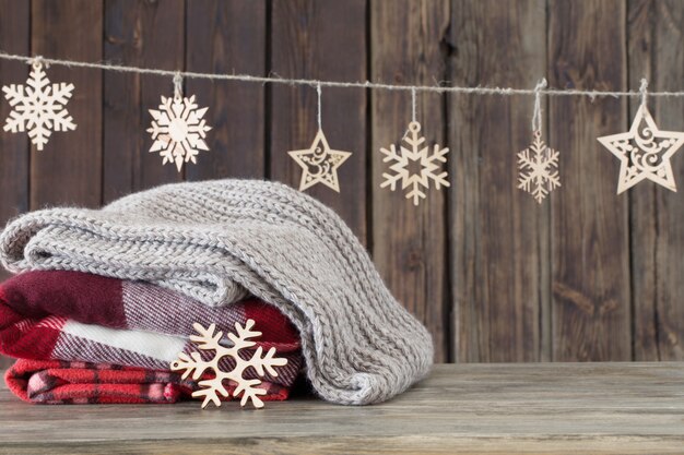 Stack of plaids and Christmas decorations on wooden wall