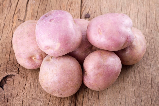 Photo stack of potatoes on wooden table solanum tuberosum