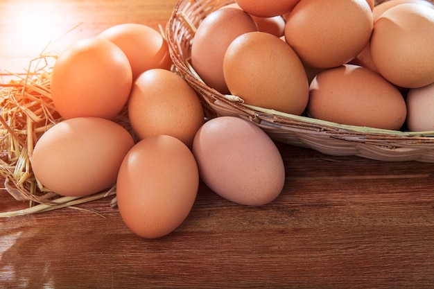 Stack of raw eggs in natural basket on wood table