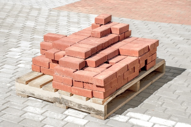 Stack of red bricks on sidewalk.