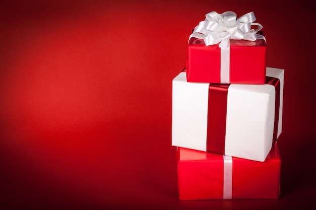 Stack of red and white christmas gift boxes on red background