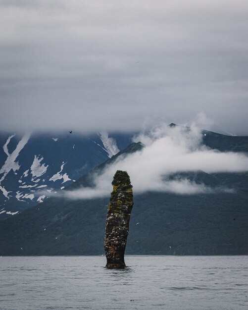 Photo stack rock in sea with mountains in background