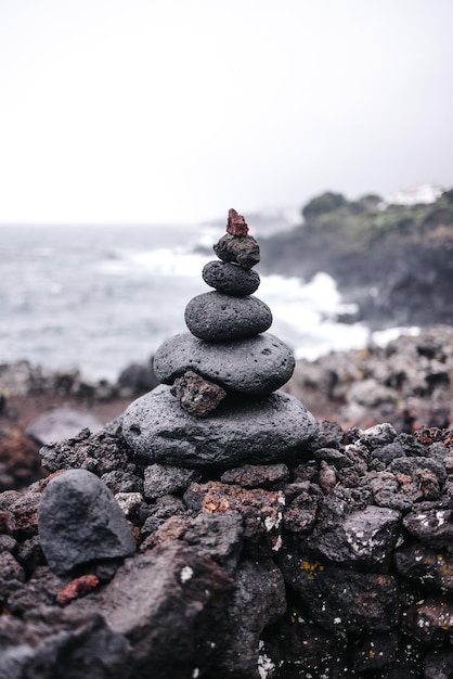 A stack of rocks on a beach with a sea in the background.