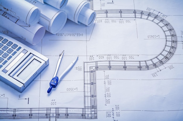 Stack of rolled blueprints calculator compass construction concept