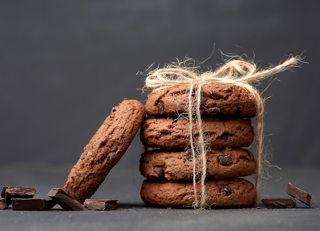 Stack of round chocolate chip cookies tied with a rope on a black board