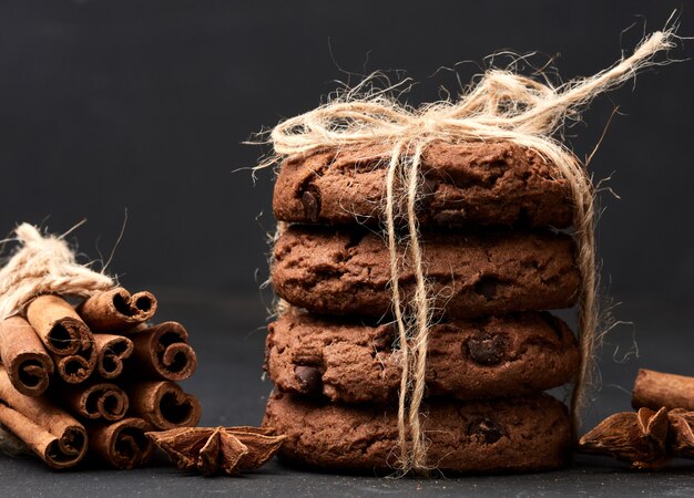 Foto pila di biscotti di pepita di cioccolato rotondi legati con una corda su un bordo nero