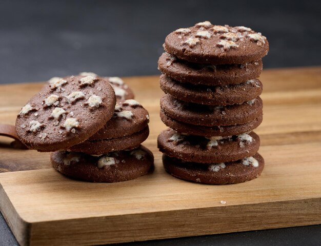 Foto una pila di biscotti rotondi di cioccolato su uno sfondo nero