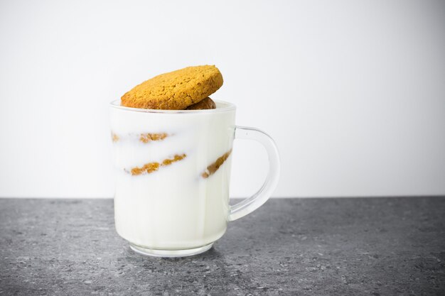 Stack of round cookies soaked in milk in a transparent glass cup