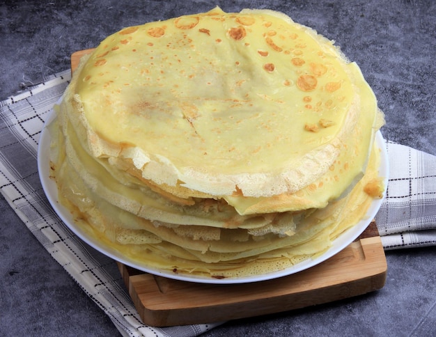 A stack of round thin pancakes on a wooden kitchen board