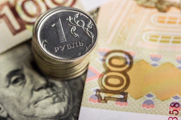 A stack of Russian coins on money background: Russian rubles and US dollars