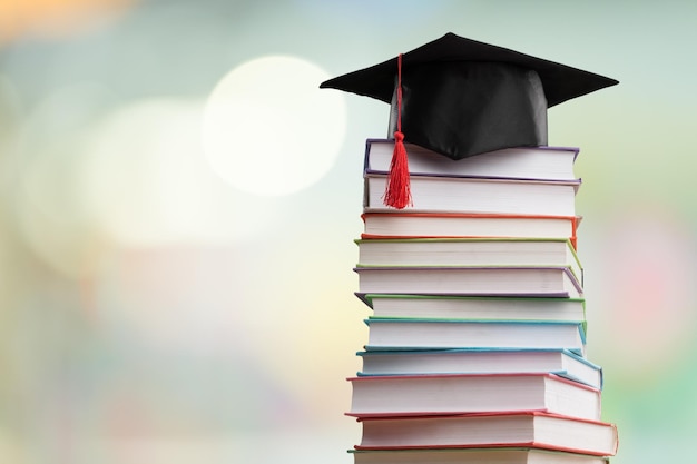 Stack school books with black graduation hat