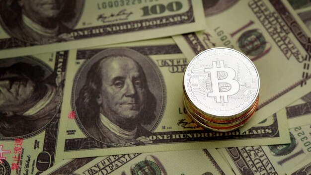 Stack of silver coins with cryptocurrency sign and symbol on pile of dollar banknote. Idea for blockchain, the new type of money in the economy of the business world.