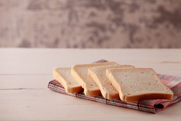 A stack of sliced bread toasts on white wooden background