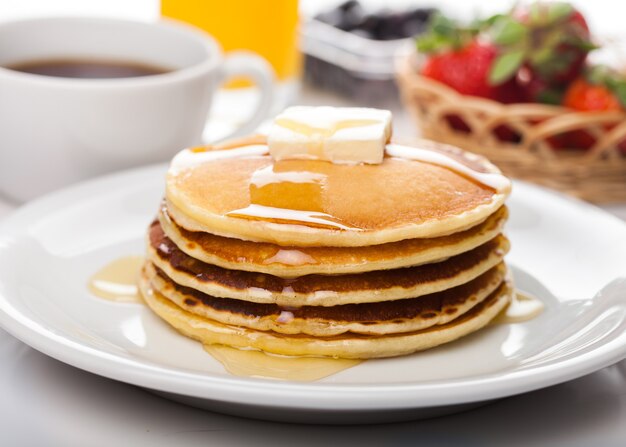 Stack of Small pancakes in syrup on background