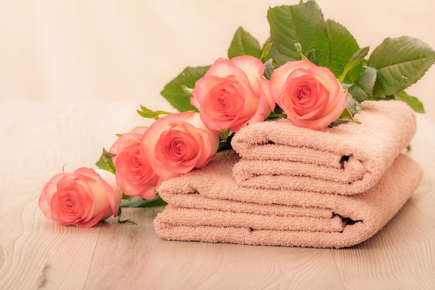 Stack of soft terry towels with red roses in pink background.