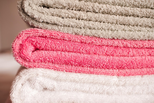 Stack of soft towels staying in bed in hotel room close up. Selective focus.