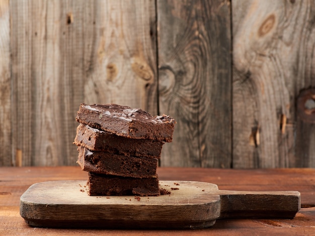 Pila di fette al forno quadrate di torta al cioccolato brownie con noci