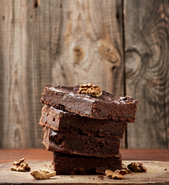 Pila di fette al forno quadrate di torta al cioccolato brownie con noci